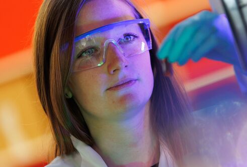 woman looking at computer screen while wearing safety glasses