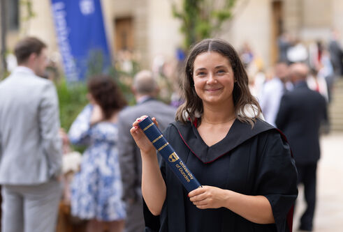 Woman in graduation gown holding a scroll