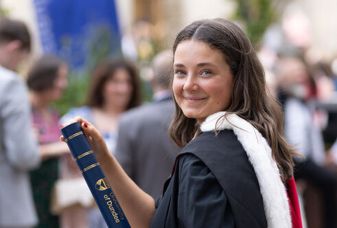 student holding graduation scroll