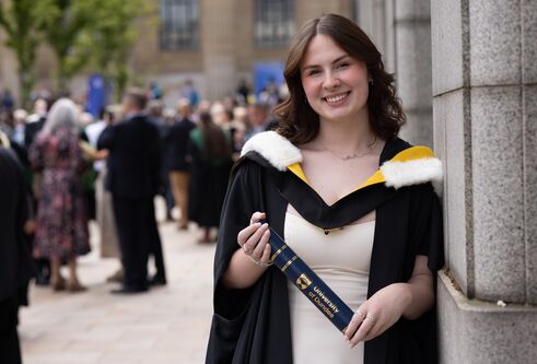 student holding graduation scroll