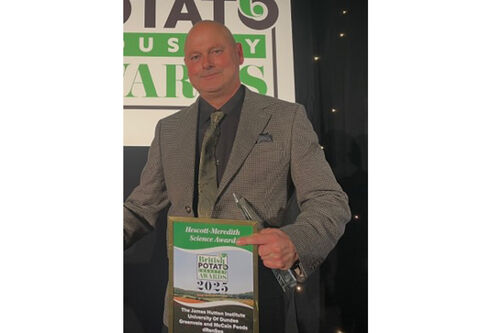 A man smiling while holding an award