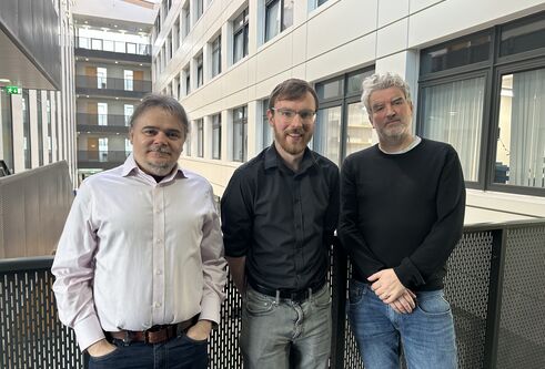 Three men stood side by side smiling