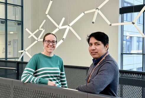 Two people stood smiling in front of a light installation