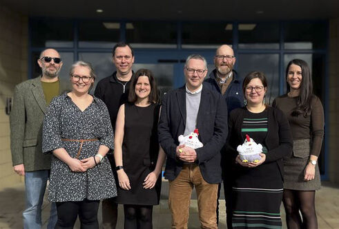 A group of people stand outside a building in the entryway.