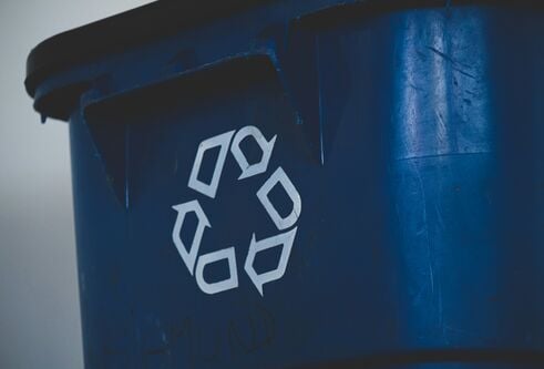 A recycling symbol on the front of a green bin