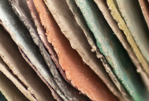 Artwork as part of the DJCAD Masters Showcase of an abstract sculpture of stacked, hand-cut coloured paper discs forming curved, tubular loops with textured edges