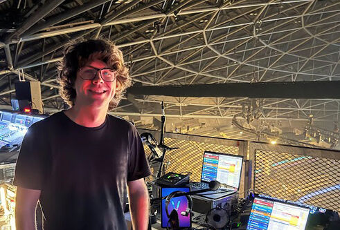 Lewis, standing on the left of the image, infront of an empty OVO Hydro arena