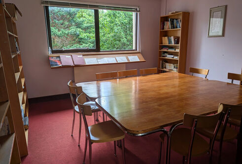 A large table with several chairs located in the Chaplaincy