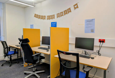A small room with height-adjustable desks, ergonomic chairs and printers