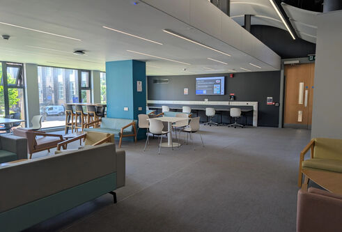 A large room with high stools, cafe seating and soft chairs.