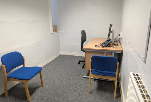 A small room with an office chair, table and computer