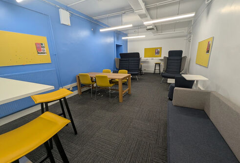 A room with two high back chairs, table surrounded by chairs and a sofa