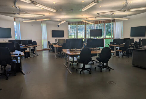 An IT lab in the Queen Mother building with office chairs, desks and computers