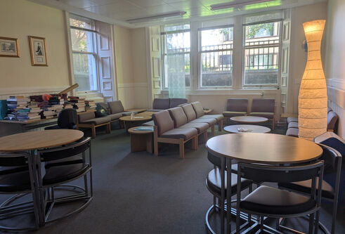A room with soft furnishings and two round tables with chairs 