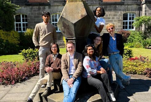 Members of the DUSA exec posing around a sundial in the Geddes Quad on a sunny day