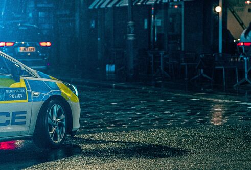 A police car parked at night on a cobbled street