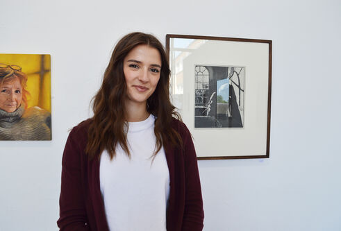 A person stands in front of artwork hanging on a wall