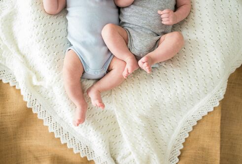 The lower body of two babies, side by side.