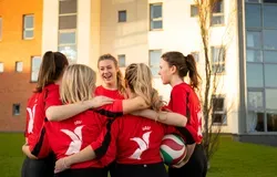 University of Dundee Women's volleyball team in a group huddle.