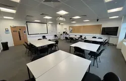 Dalhousie 1S05 - four sets of square tables surrounded by chairs with a tv screen in the corner and a white screen at the front of the room