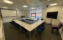 Dalhousie 2F02 - tables set in an oblong with chairs. A mobile tv screen and a white screen on the wall