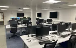 IT Suite in Tower basement showing several desks in rows with computers, mouse and keyboards