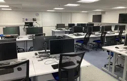 IT Suite in Tower Basement, Suite E showing several desks in a row with computer screens, keyboards and mouse