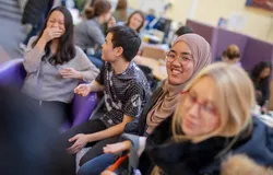 A group of students chatting and laughing in the Global Room
