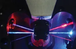 Photograph of 3 laser beams focussed through a lens, with 3 lasers of different colours leaving the lens