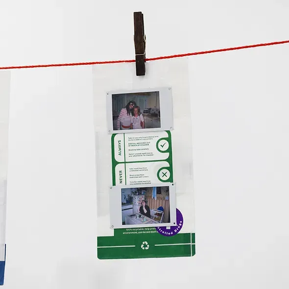 photographs and prescription packaging clipped to a clothesline, displayed as part of an art and philosophy graduate showcase