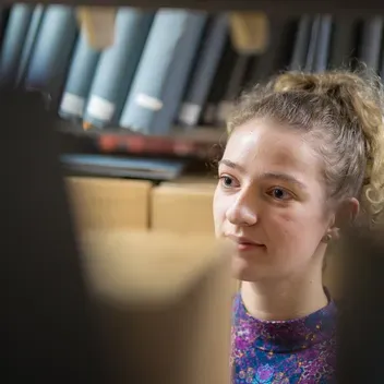 Girl looking at old books in an archive
