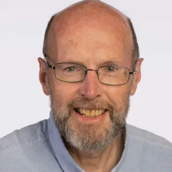 head shot of man wearing light blue shirt and thin glasses