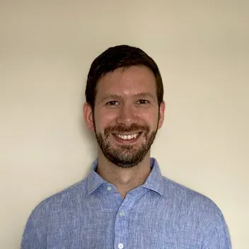 Daniel Courtney wearing a blue shirt smiling.