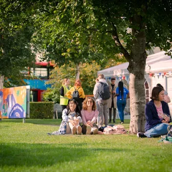Students sitting on grass at campus green