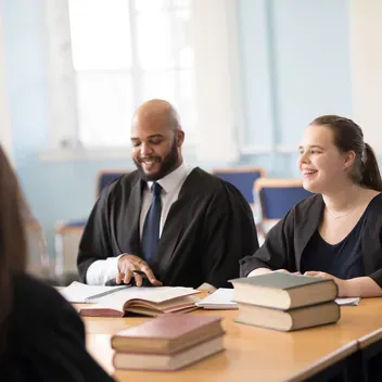 Law students having a meeting at a table with books on it. 