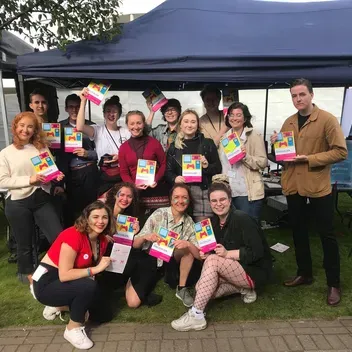 students at a stall holding magazine copies
