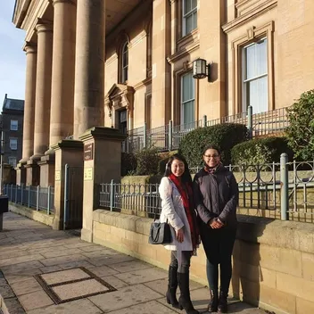 two students outside a stone building with pillars