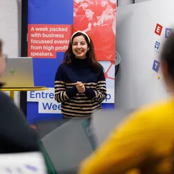 A woman confidently presenting to a group of attentive individuals during a professional meeting.