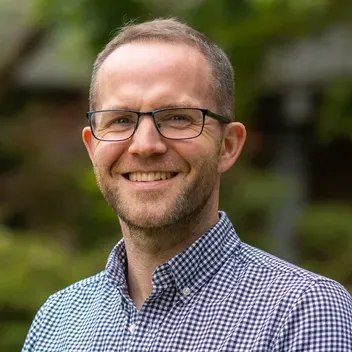 Portrait of Daryll Archibald with blurred trees in the background.