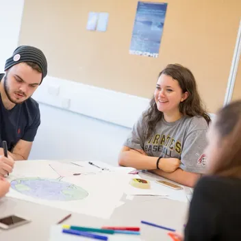 Group of students sitting at a table studying and chatting together