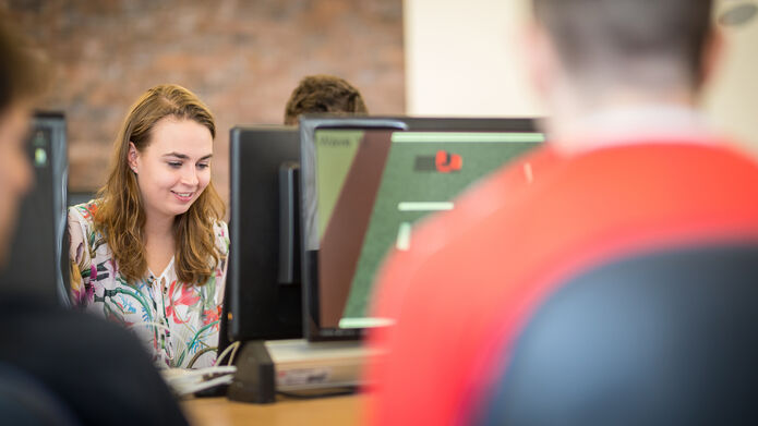 Students working on computers around a desk