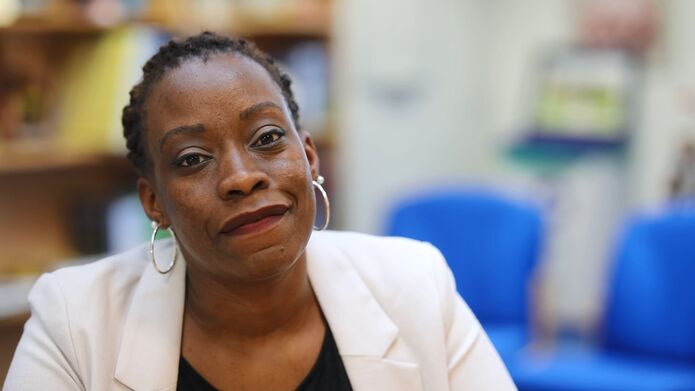 an image of Mariam Kiggundu sitting in a room with blue chairs in the background