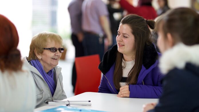 older woman sitting with younger woman around a table