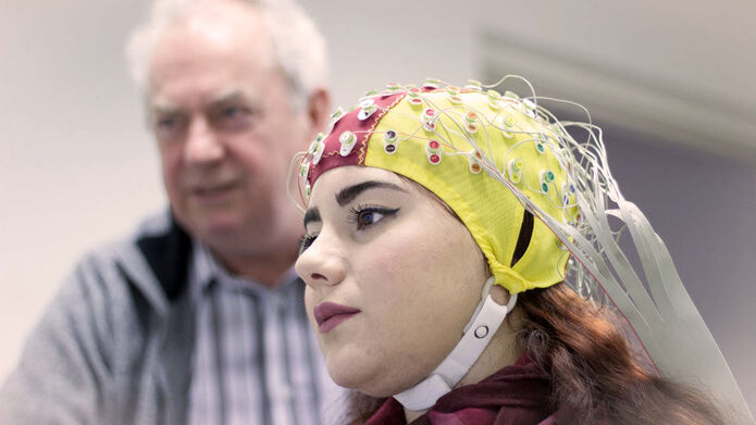 Girl wearing brain cap with man mid experiment
