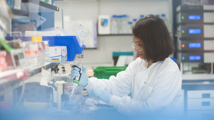 Scientist using syringe to fill up container in lab