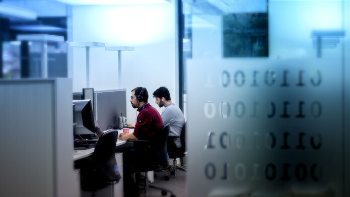 scientists sitting side by site, working on computer screens in a computer lab