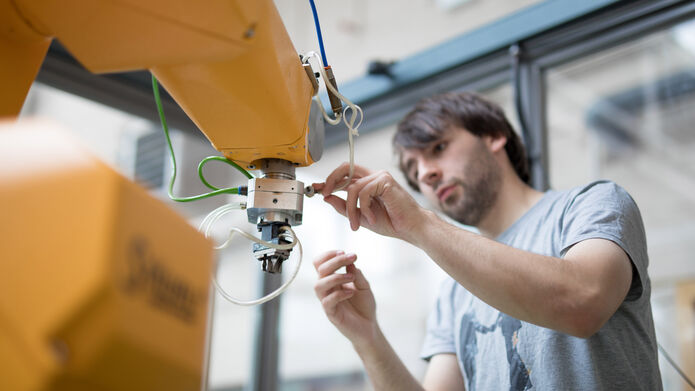 A student adjusts the head of a robotic arm