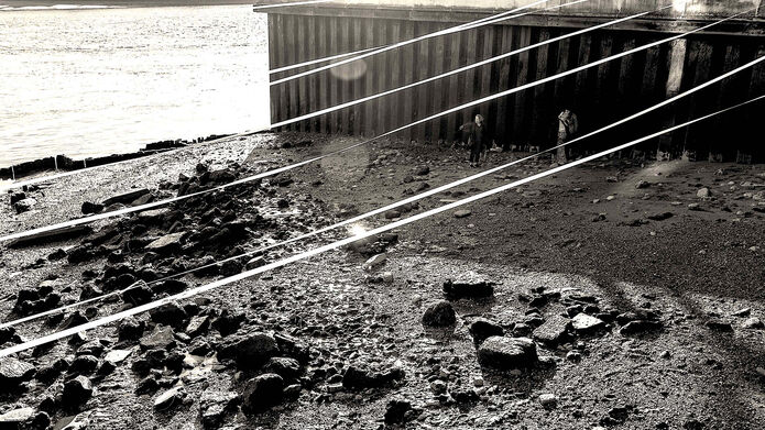 Black and white photo of two people next to water with white lines floating above their heads