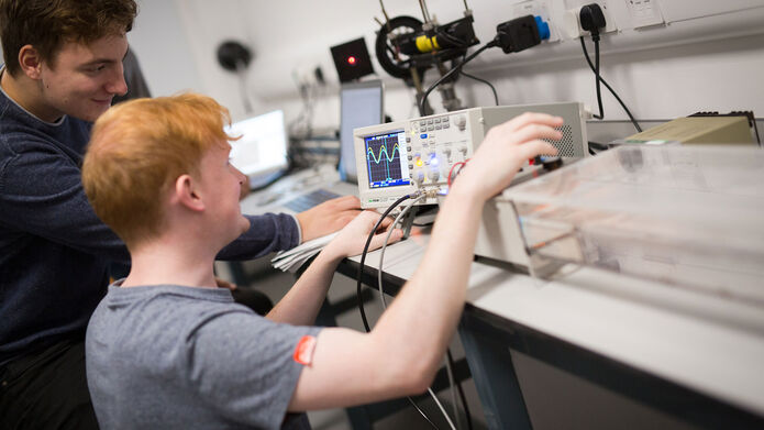 Two people working in a laboratory with an oscilloscope