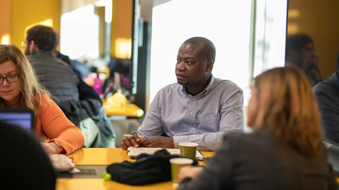 A group of people sitting around a desk in a classroom setting.